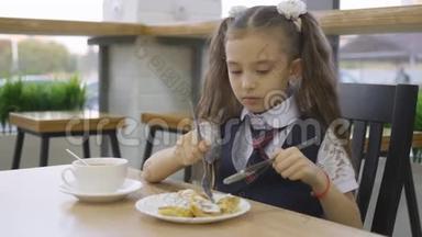 穿校服的小女孩在<strong>学校食堂</strong>吃午饭。